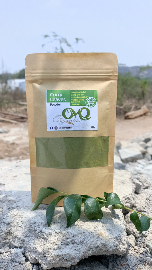 Curry Leaves Powder pouch by OhMyOrganics placed on rocks with fresh curry leaves – herbal hair growth powder.